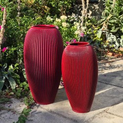 deux grands vases rouges design de tailles differentes dans un jardin