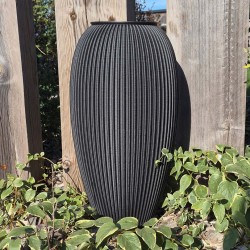 un vase xxl design gris foncé dans un jardin
